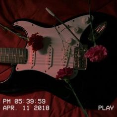 an electric guitar is laying on a bed with flowers in it and the date has been changed