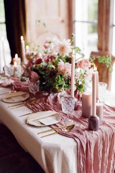 the table is set with candles, plates and napkins for an elegant dinner party