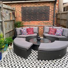 an outdoor seating area with black and white checkered flooring, grey wicker couches and round coffee table