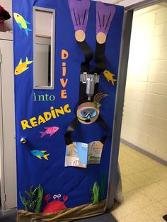 a blue door decorated with hand prints and fish on it, reads dive into reading