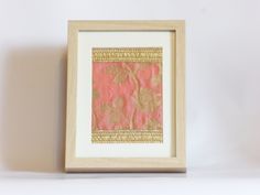 a white and wooden frame with a pink flower design on the front in gold foil