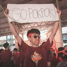 a young man holding up a sign that says go porkpok in front of him