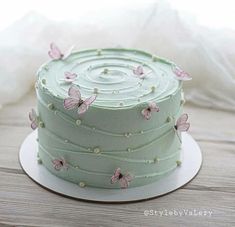 there is a green cake with pink butterflies on it