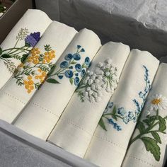 a box filled with white napkins covered in embroidered flowers