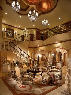 a living room filled with lots of furniture and chandelier above the staircases