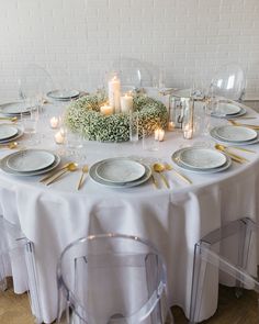 a white table topped with plates and candles