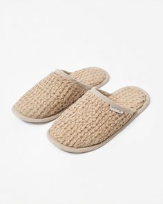 a pair of beige slippers sitting on top of a white surface