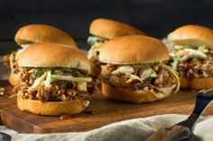 four pulled pork sliders with coleslaw and slaw on a cutting board