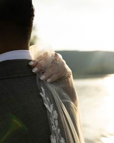 a bride and groom embracing each other by the water