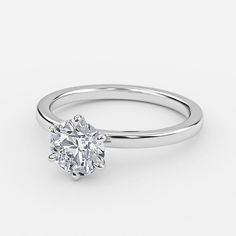 a white gold engagement ring with a round brilliant cut diamond in the center, on a plain surface