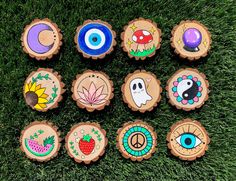 the wooden badges are painted with different designs and colors, including an eye, sunflower, mushroom, pineapple, leaf, flower, bird, owl