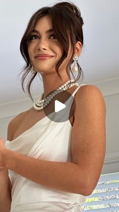 a woman in a white dress is smiling and holding a cell phone with her right hand