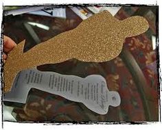 a person holding up a piece of paper with gold glitter on it and a bookmark in the shape of a dog bone