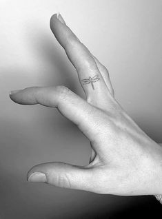 a person's hand with a small cross tattoo on their left thumb and fingers