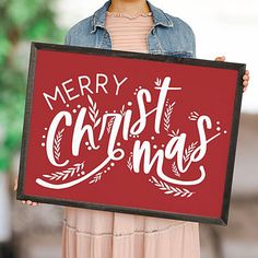 a woman holding up a merry christmas sign