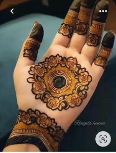 a woman's hand with henna tattoos on it and an ornate ring in the middle