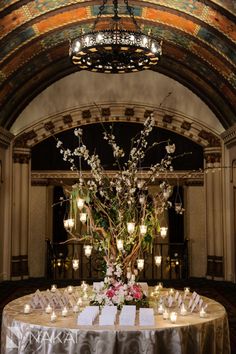 a table with candles and flowers on it in front of an ornate chandelier