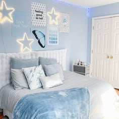 a bedroom with blue walls, white bedding and stars on the wall above it