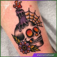 a skull with a candle and flowers on it's leg is seen in this tattoo design