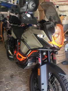 a motorcycle parked inside of a garage next to a pile of boxes on the floor