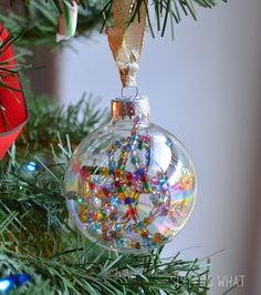 a glass ornament hanging from a christmas tree filled with beads and other decorations