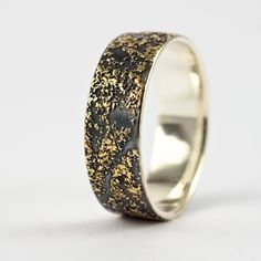 a wedding ring with gold and black speckles on the inside, against a white background