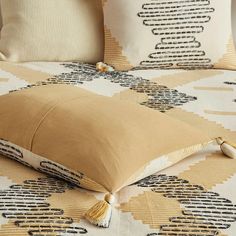 a close up of a pillow on a bed with decorative patterns and tassels