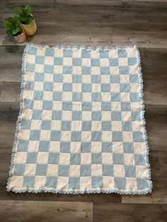 a blue and white checkered rug on the floor next to a potted plant