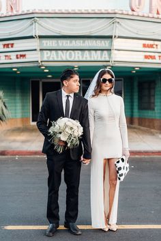 a bride and groom standing in front of a theater