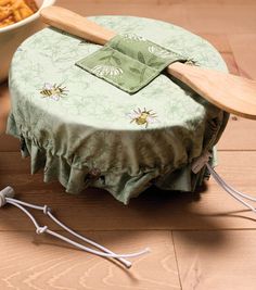 a round table with a green cover and two wooden spoons on top of it