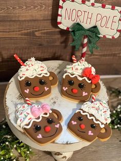 four decorated christmas cookies sitting on top of a white plate next to a sign that says north pole