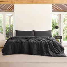 a bed with black sheets and pillows in a room