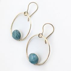 "These modern hoop earrings are made of 14k yellow gold filled wire hoops with a natural aquamarine cabochon in a sterling silver bezel. The ear wires are also 14k gold filled. Gold filled metal has a higher gold content and does not wear off like plating. It has been used by jewelers for many years, in Victorian times it was called rolled gold. The large, 10mm, natural aquamarine cabochons are opaque and have a strong blue hue. Each hoop is 1 1/2\" inch in length with a diameter of 1 1/4\" inch 14k Gold Filled Oval Earrings With Ear Wire, Modern Wire Wrapped Round Hoop Earrings, Everyday Oval Jewelry With Ear Wire, Modern Wire-wrapped Round Hoop Earrings, Modern Wire Wrapped Round Jewelry, Modern Round Wire Wrapped Jewelry, Handmade Oval 14k Gold Filled Earrings, Modern Wire Wrapped Hoop Jewelry, Oval 14k Gold-filled Earrings With Ear Wire