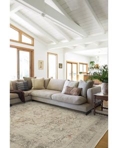 a living room with a couch, rug and windows