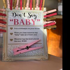 a sign that says don't say baby with clothes pins attached to it and scissors in the middle