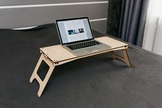 a laptop computer sitting on top of a wooden desk with an elevated bed tray attached to it