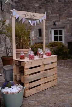 a wooden cart with jars and flowers on it sitting in front of a stone building