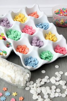 there are many different colored confetti in the trays on the table with sprinkles