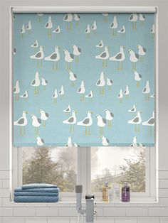 a bathroom window with birds on it and blue towels in front of the window sill