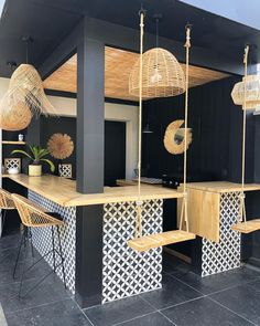 a black and white kitchen with wooden accents on the counter top, hanging baskets over the island