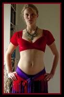 a woman in a red top and purple skirt with her hands on her hips posing for the camera