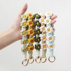 a hand holding four bracelets with flowers on them