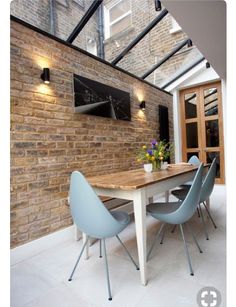 a dining room table with blue chairs under a skylight