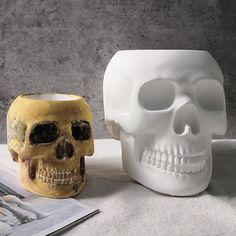 there are two skulls sitting next to each other on the table, one is white and the other is yellow