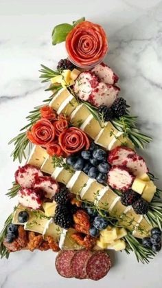 a christmas tree made out of cheese, berries and other foods on a marble table