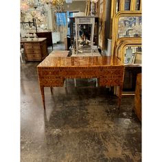 an antique desk in the middle of a room with mirrors and other antiques behind it