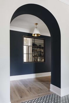 an arch in the hallway is decorated with black and white tiles, gold accents and a mirror