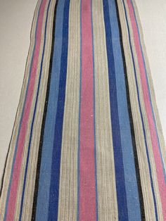 a blue, pink and white striped pillow sitting on top of a floor next to a wall