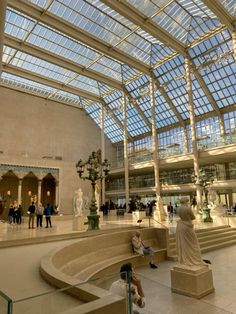 the inside of a large building with many statues and people walking around in front of it