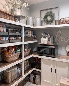 a kitchen with white cabinets and shelves filled with food